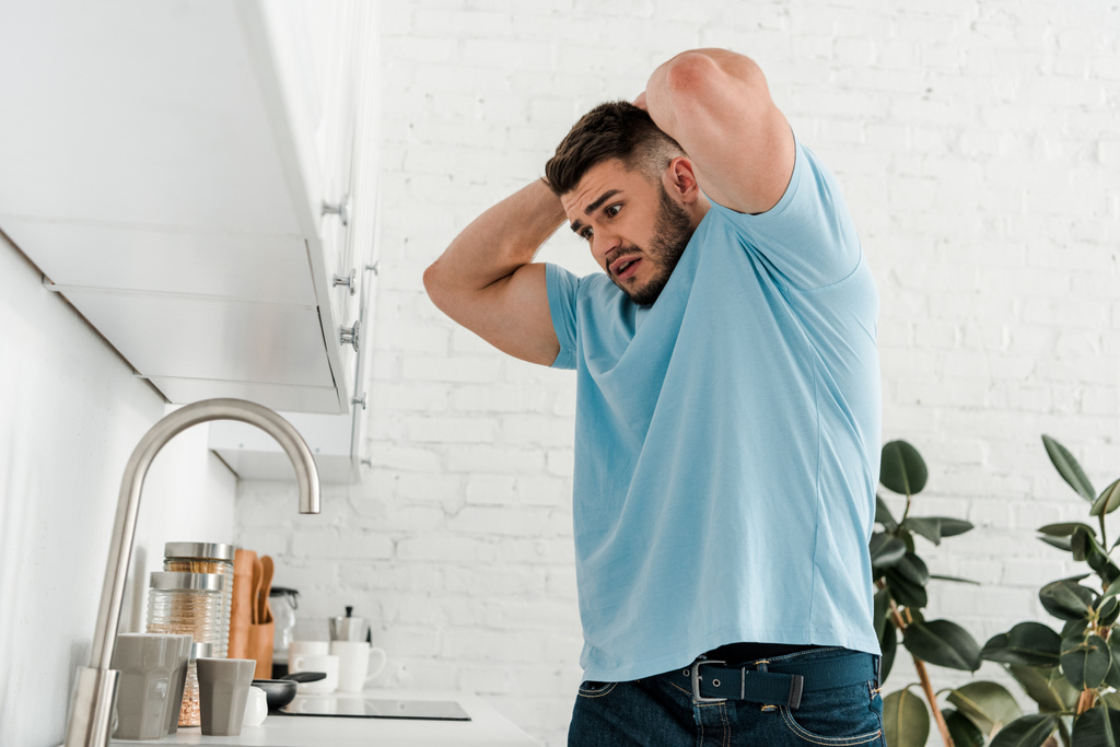 stressaantunut mies koskettaa päätä, kun tarkastellaan pesuallas moderni keittiö
  - Valokuva, kuva