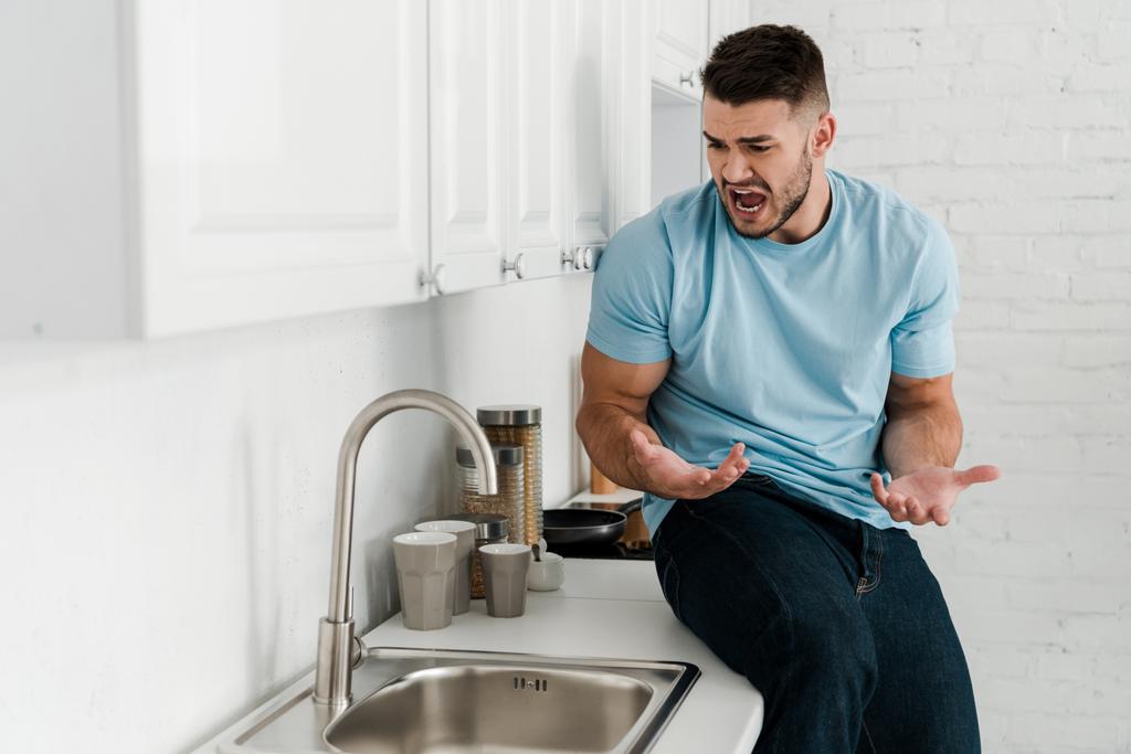 üzgün adam gesturing ve mutfakta musluk yakınında çığlık  - Fotoğraf, Görsel