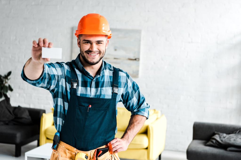 travailleur joyeux tenant carte blanche et debout avec la main sur la hanche
  - Photo, image