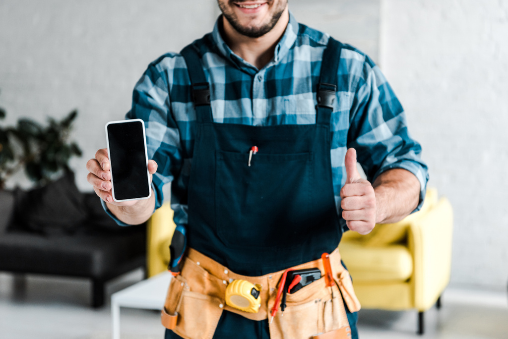 oříznutý pohled na vousatého muže přidržující telefon Smartphone s prázdnou obrazovkou a ukazující palec nahoru  - Fotografie, Obrázek