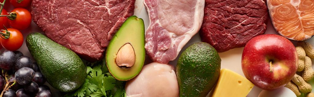 Panoramic shot of raw meat, fish and poultry near avocados, tomatoes, grape, apple cheese and peanuts - Photo, Image