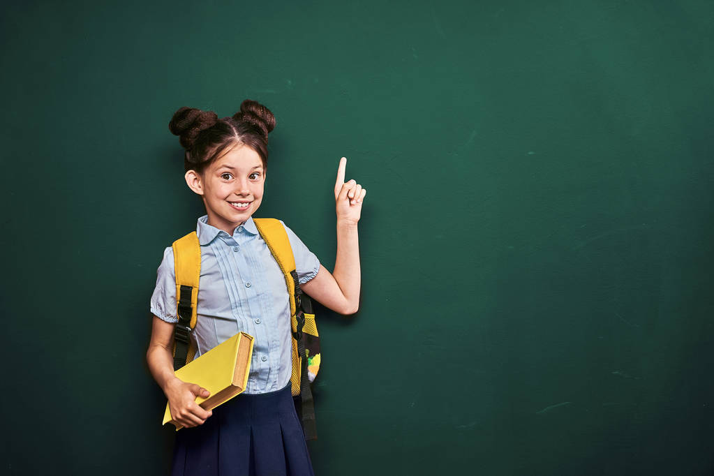 Маленькая девочка, студентка показывает пальцем. позитивная школьница в т
 - Фото, изображение