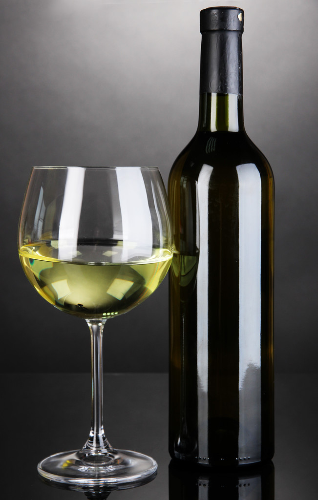 Valkoviini lasi ja pullo viiniä harmaalla pohjalla
 - Valokuva, kuva