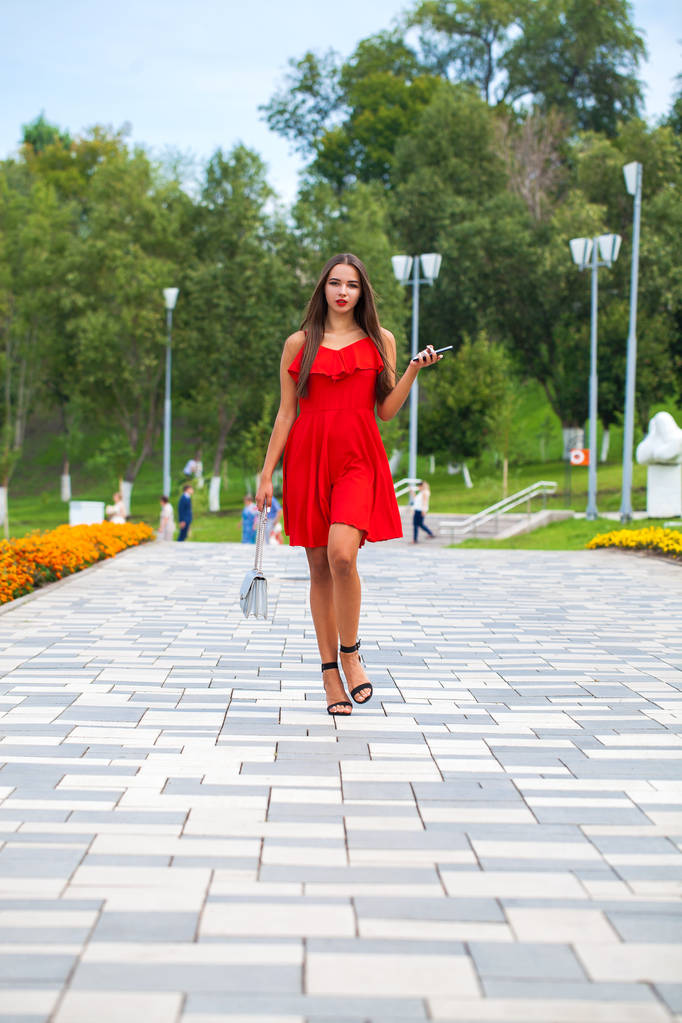 Joven modelo hermosa en vestido rojo caminando en la calle de verano
 - Foto, Imagen