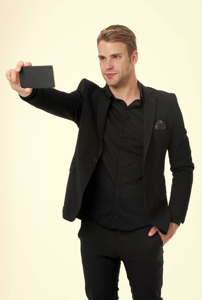 Selfie を取る。自信のビジネスマンは、スマート フォン ホワイト バック グラウンドを使用します。ビジネス コミュニケーションの概念。男のスーツのビジネスマンは、現代のモバイル技術を事業に活用します。モバイル通信 - 写真・画像