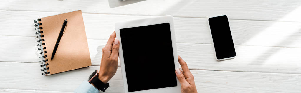 tiro panorâmico de mulher segurando tablet digital com tela em branco perto de smartphone e notebook com caneta
  - Foto, Imagem