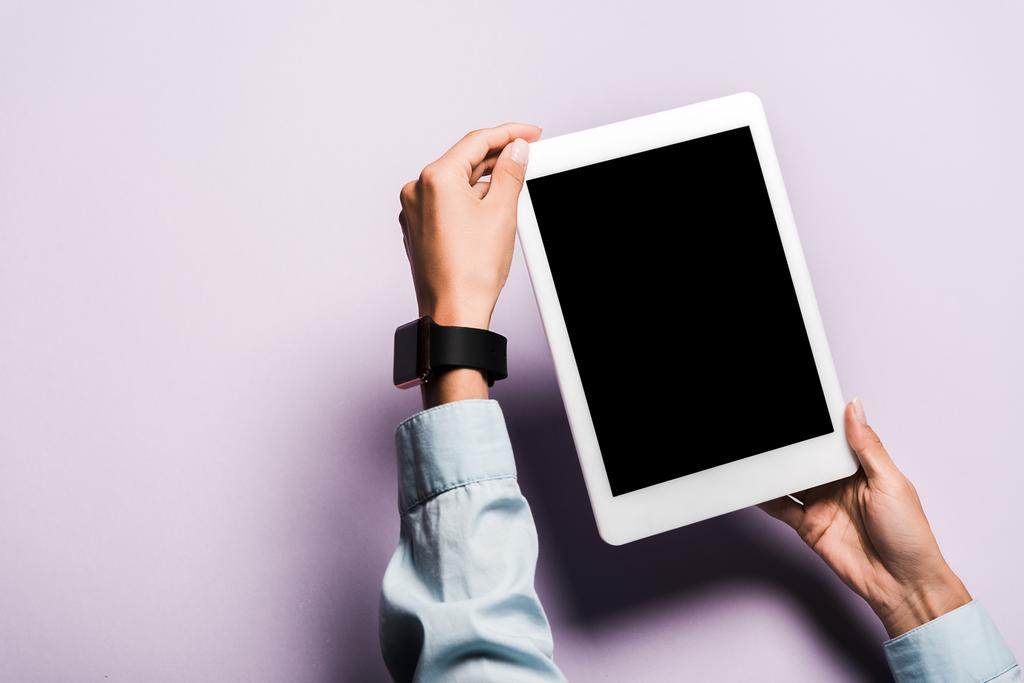 vista ritagliata della donna con orologio intelligente a portata di mano tablet digitale con schermo bianco sul viola
  - Foto, immagini
