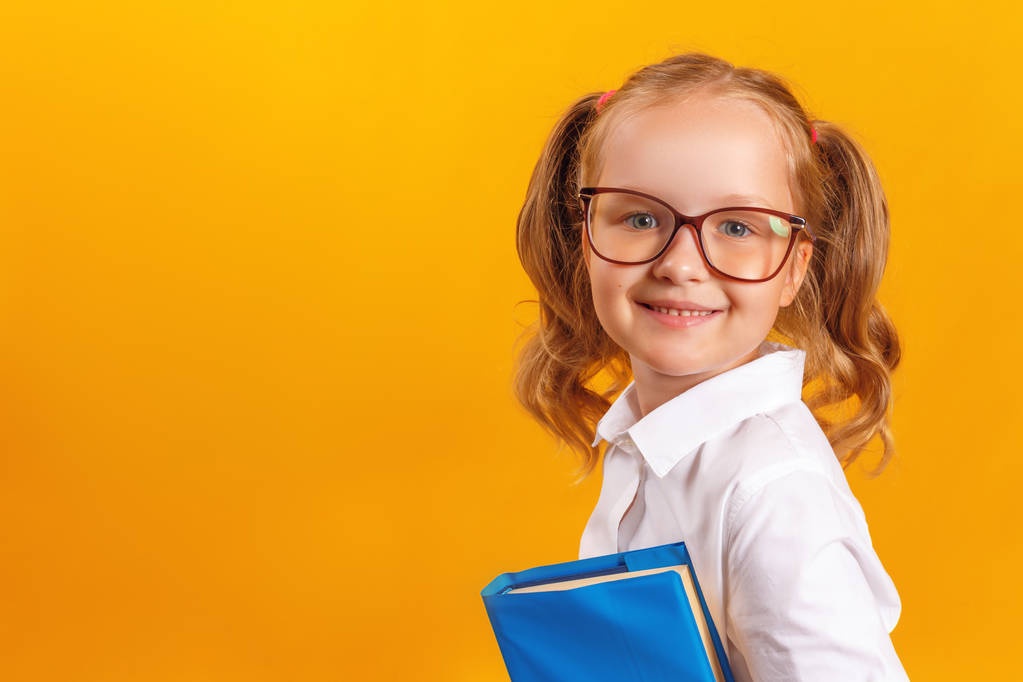 Le concept d'éducation et d'école. Joyeux petit étudiant en lunettes tenant des livres sur un fond jaune. Espace de copie
. - Photo, image