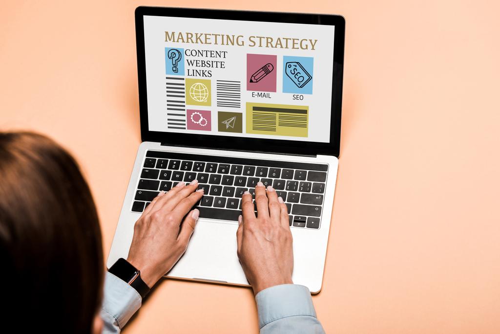 обрезанный вид женщины, печатающей на ноутбуке с маркетинговой стратегией буквы на розовый
  - Фото, изображение