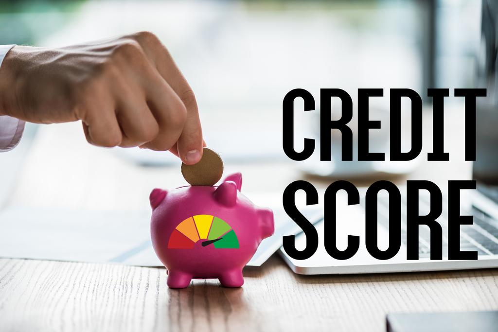 vista recortada de hombre de negocios poner moneda en alcancía rosa cerca de letras puntuación de crédito y portátil
  - Foto, Imagen