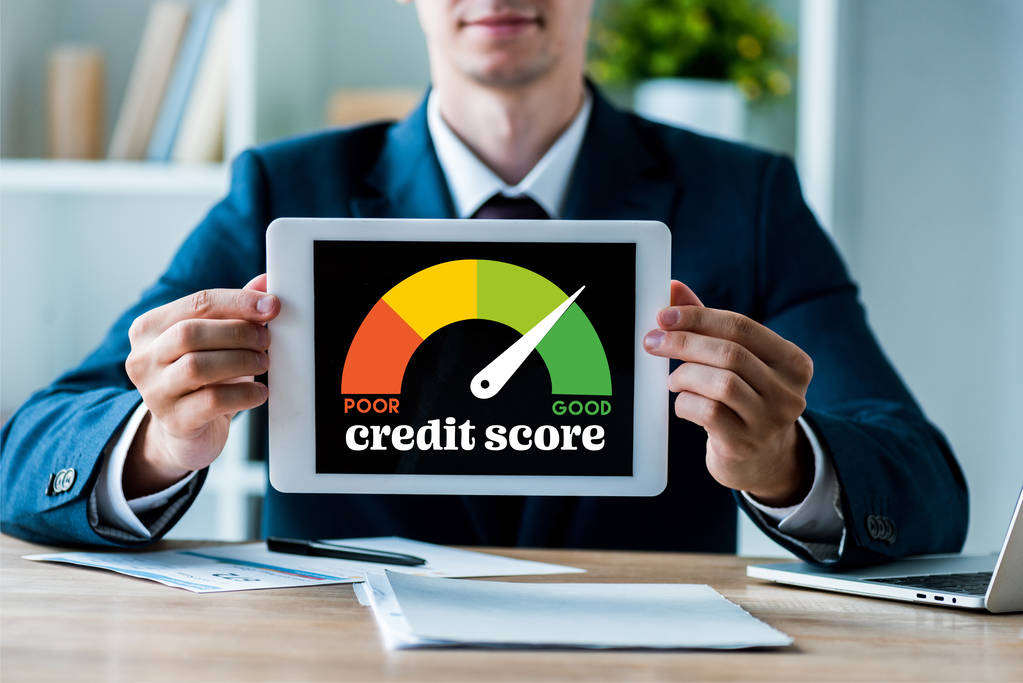 selective focus of happy man holding digital tablet with credit score lettering in office  - Photo, Image