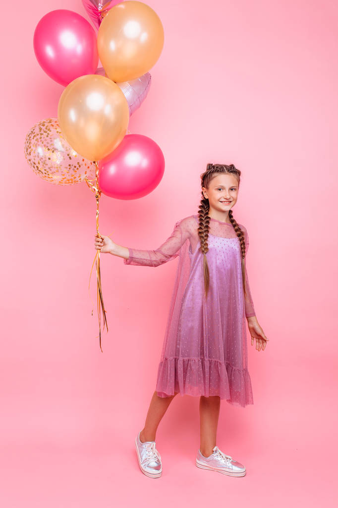 Ευτυχισμένος και όμορφη έφηβος κορίτσι κρατώντας ένα μάτσο πολύχρωμο αερόστατο - Φωτογραφία, εικόνα