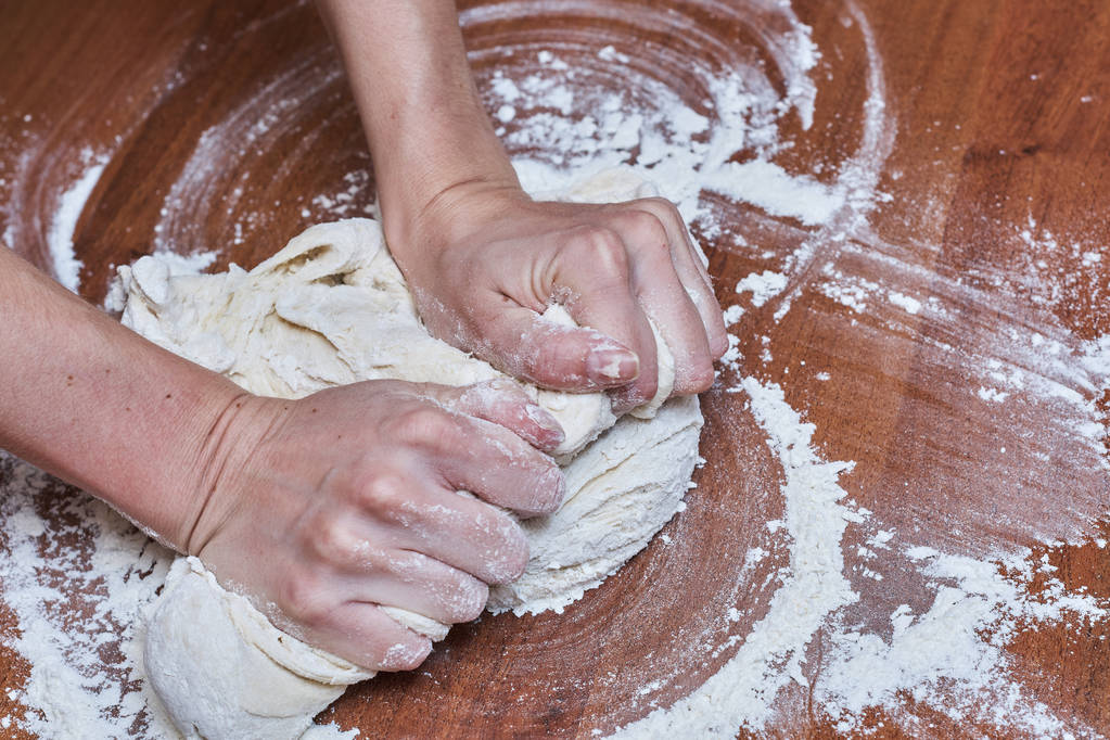 Жіночі руки шеф-кухар крупним планом, замішують тісто, готують тісто на столі
 - Фото, зображення
