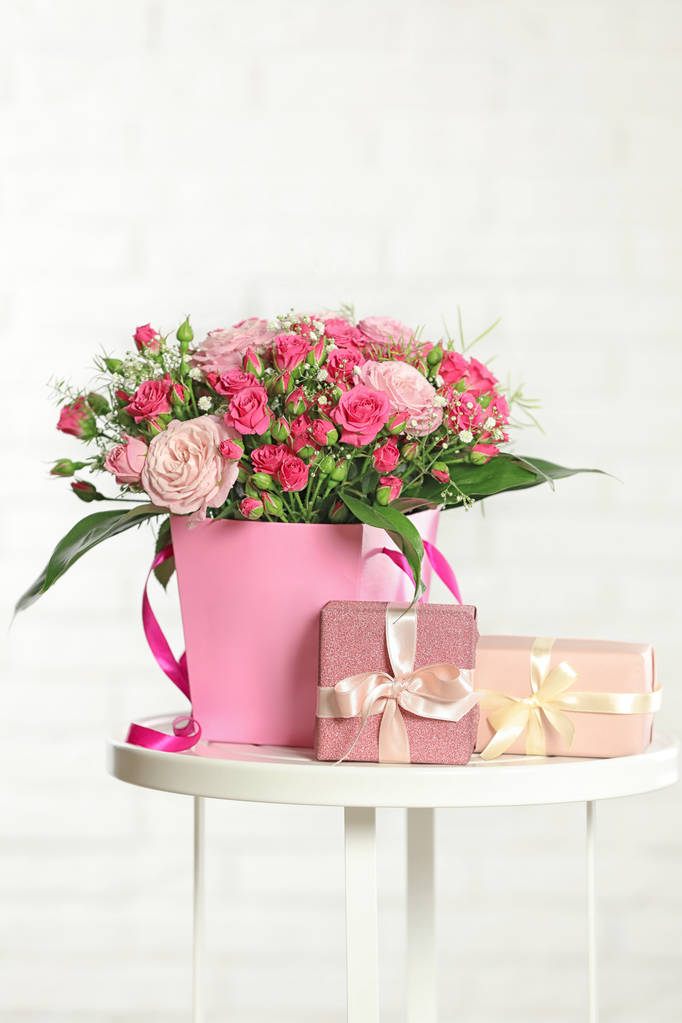 Bellissimo bouquet di fiori e scatole regalo sul tavolo sullo sfondo chiaro
 - Foto, immagini