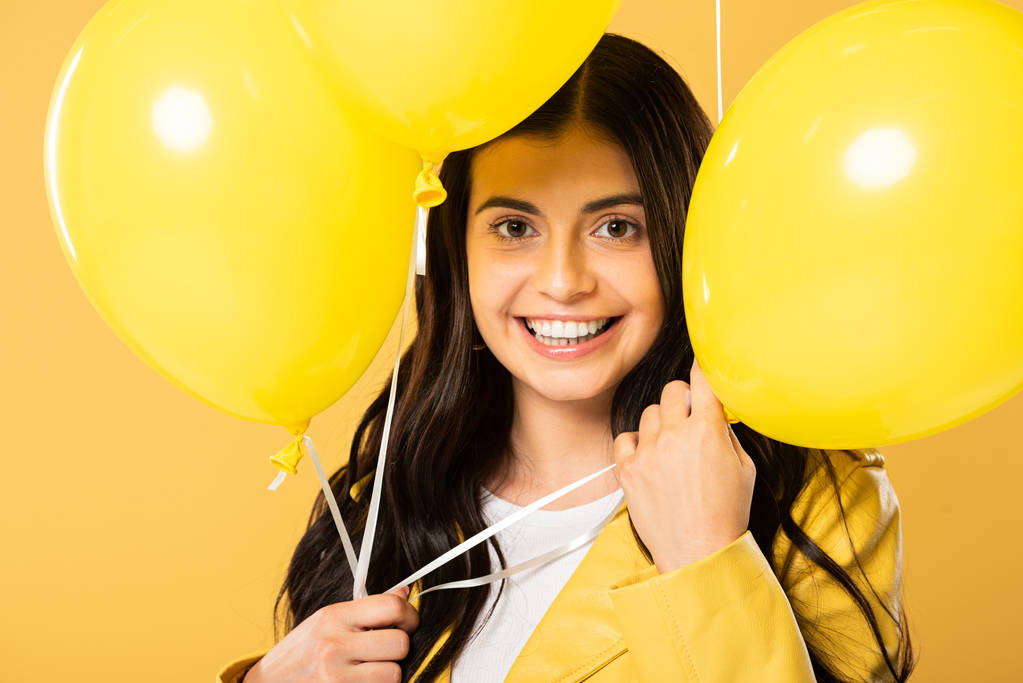 усміхнена жінка тримає жовті кульки, ізольовані на жовтому
 - Фото, зображення