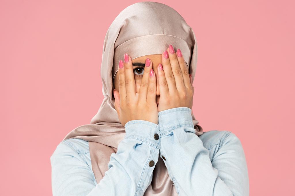 beautiful frightened muslim girl in hijab closing face, isolated on pink - Photo, Image