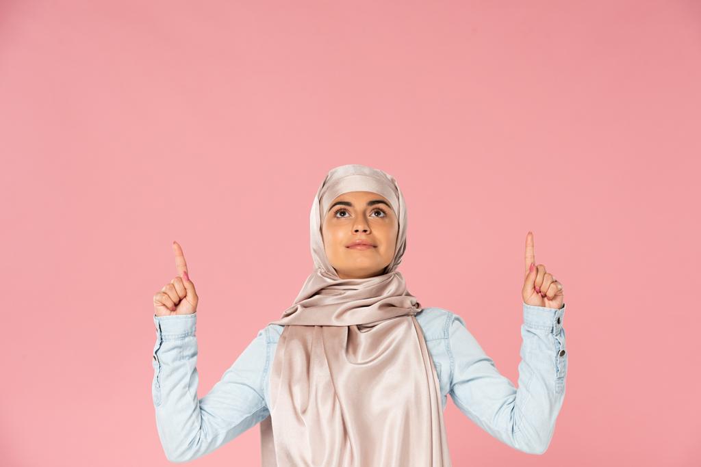 όμορφη ισλαμική γυναίκα στη μαντίλα που δείχνει, απομονώνεται σε ροζ  - Φωτογραφία, εικόνα