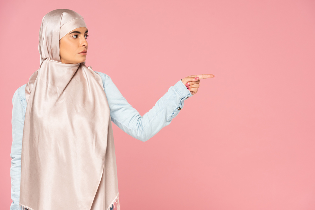 belle femme islamique en hijab montrant quelque chose, isolé sur rose
  - Photo, image