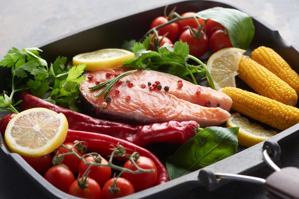 Стейк из сырого лосося со специями, овощами и зеленью на гриле
 - Фото, изображение