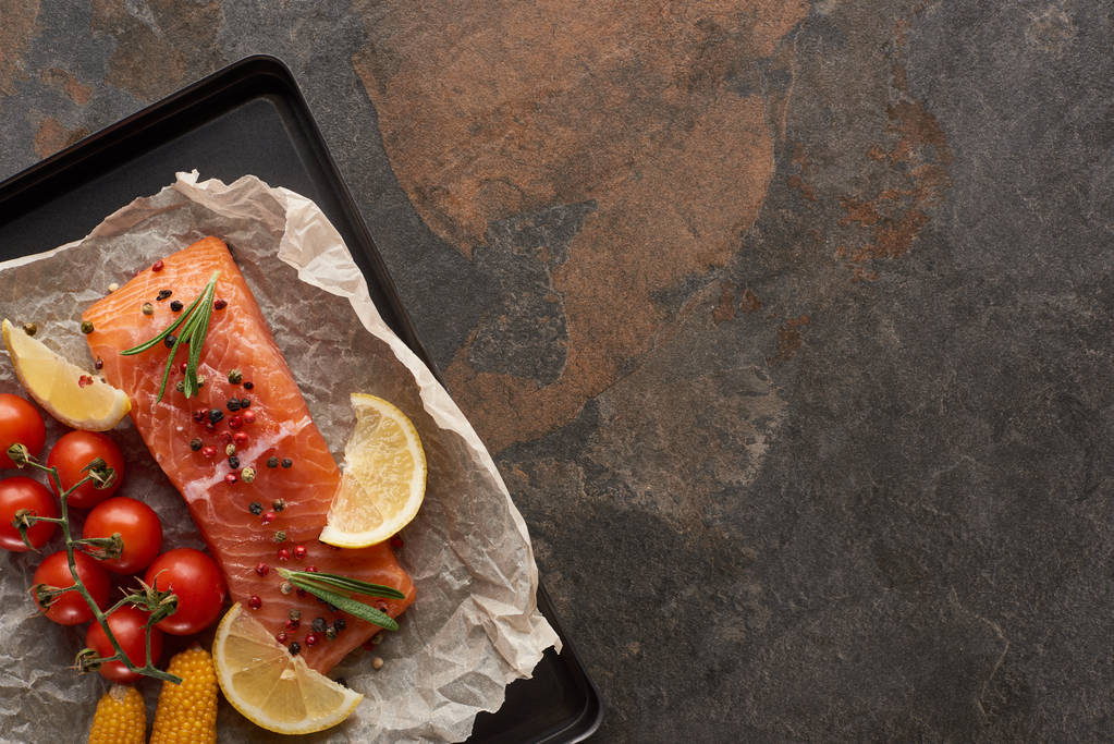 オーブントレイにトマト、トウモロコシ、レモン、ローズマリー、コショウと調理されていないサーモンステーキのトップビュー - 写真・画像
