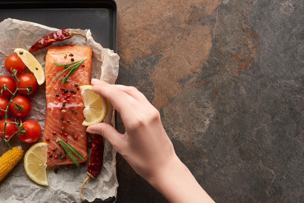 vista recortada de la mujer exprimiendo jugo de limón en filete de salmón sin cocer con verduras en bandeja del horno
 - Foto, imagen