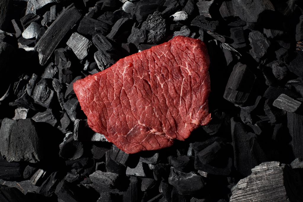a nyers marha steak és a széndarabok felülnézete - Fotó, kép