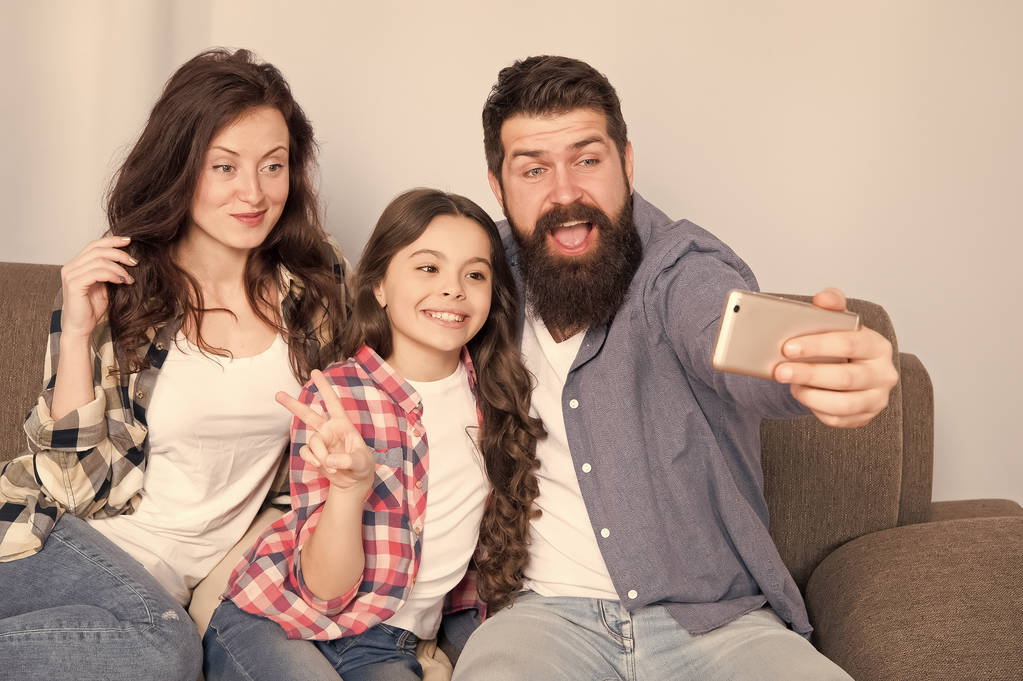 Použijte smartphone pro selfie. Přátelská rodina baví spolu. Máma táta a dcera relaxační na gauči. Rodina, pózuje pro fotografie. Zachyťte šťastné okamžiky. Rodinné selfie. Rodina spolu stráví víkend - Fotografie, Obrázek