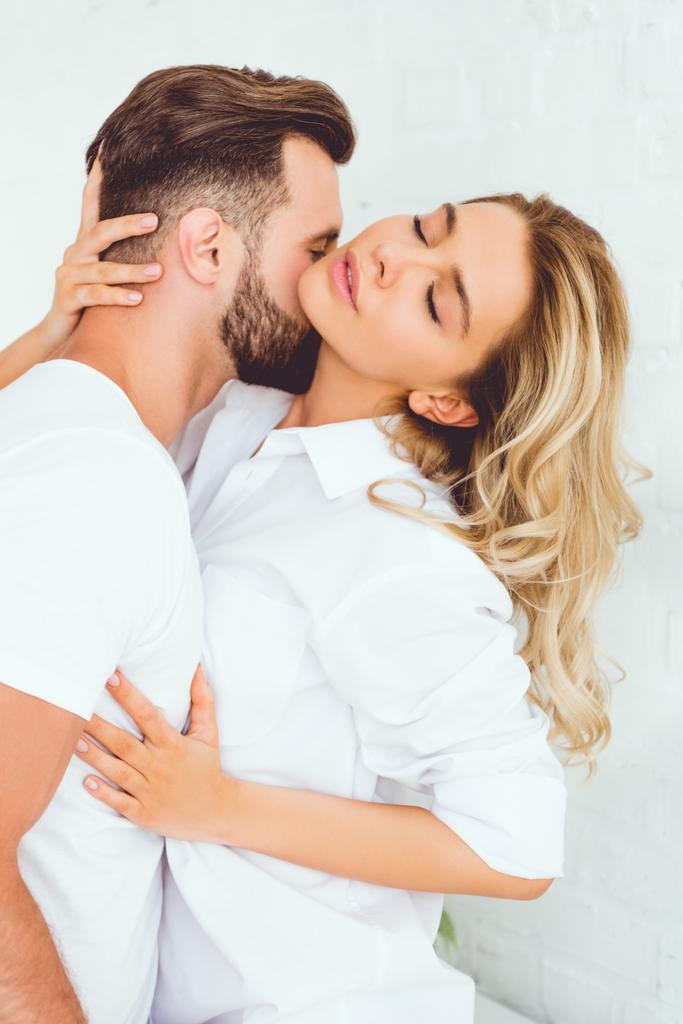 jovem abraçando e beijando namorada vestida de camisa branca
 - Foto, Imagem