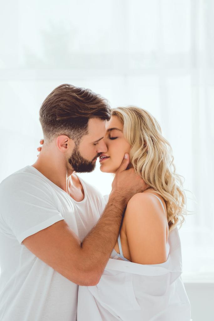 komea nuori mies syleilee ja suudella kaunis tyttöystävä kotona
 - Valokuva, kuva