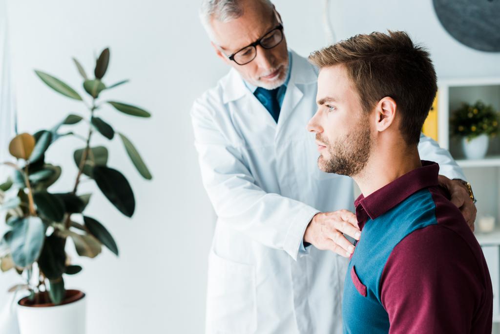 селективное внимание врача в очках и белом халате к красивому мужчине в клинике
  - Фото, изображение