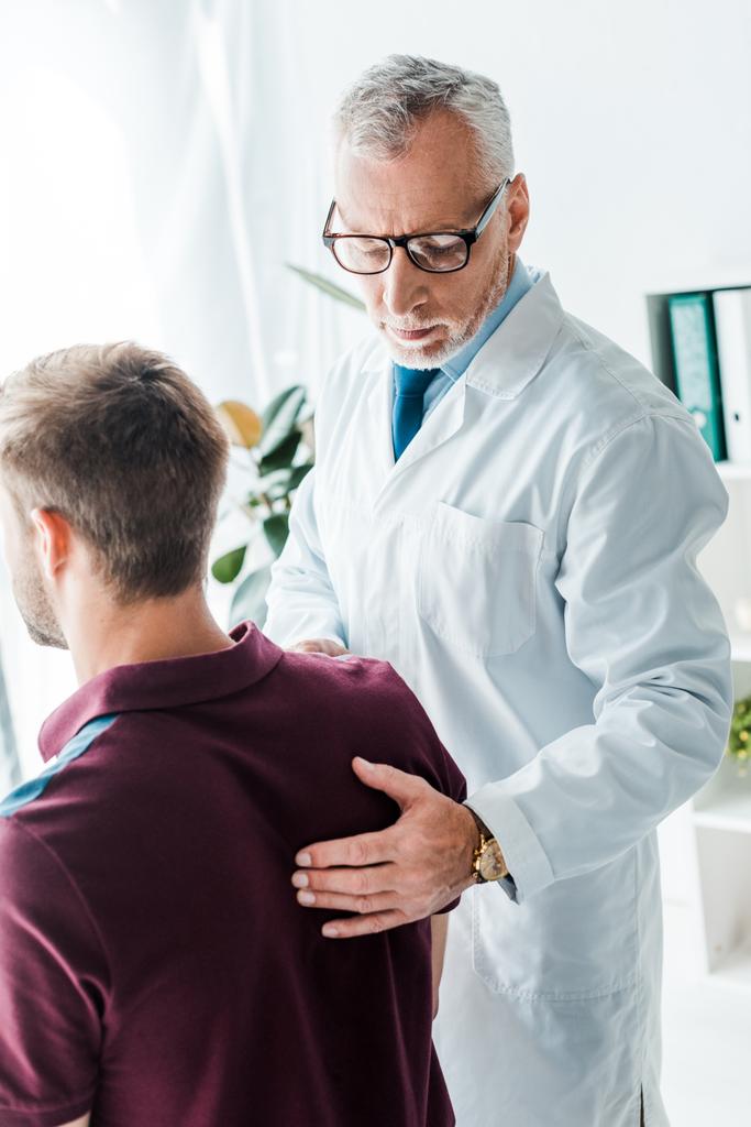 Arzt im weißen Mantel berührt Patientin in Klinik  - Foto, Bild