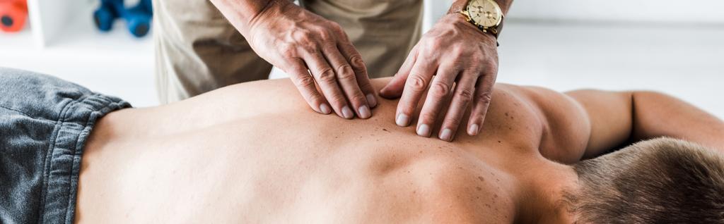 панорамный снимок мануального терапевта, делающего массаж человеку на массажном столе
  - Фото, изображение