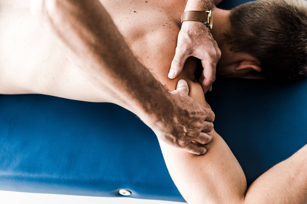 Overhead Ansicht des Mannes tut Massage zu hemdlosen Patienten  - Foto, Bild
