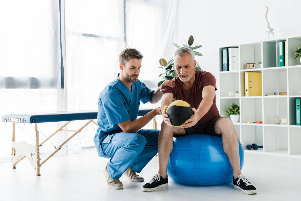  patient mature faisant de l'exercice sur balle de fitness près du médecin
  - Photo, image