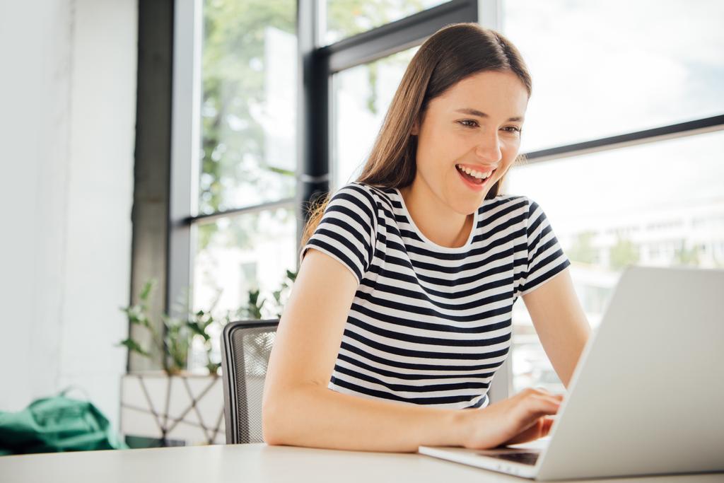 улыбающаяся девушка в полосатой футболке с ноутбуком дома
 - Фото, изображение
