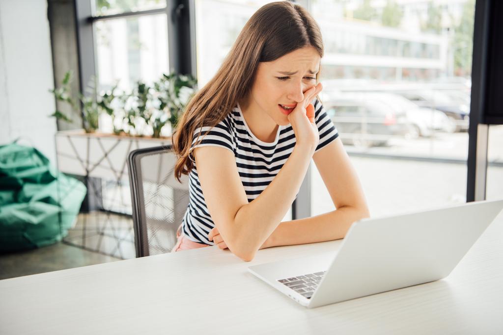 surullinen tyttö raidallinen t-paita käyttäen kannettavaa tietokonetta kotona
 - Valokuva, kuva