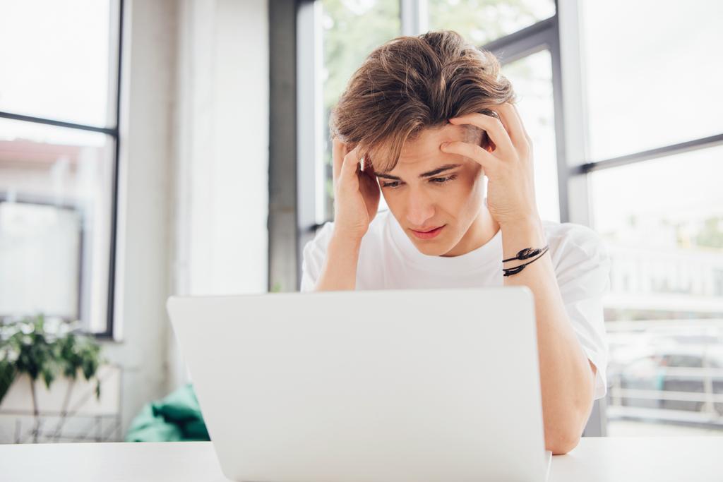 triste teen boy in bianco t-shirt utilizzando il computer portatile a casa
 - Foto, immagini