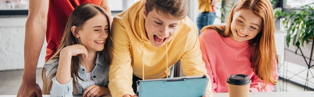 панорамный снимок улыбающихся школьников с помощью цифрового планшета в классе
 - Фото, изображение