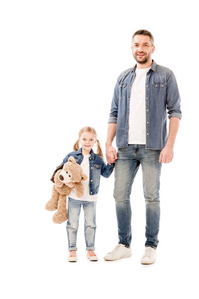 Ganzkörperansicht von lächelndem Vater und Tochter in Jeans, die Hände isoliert auf Weiß haltend - Foto, Bild