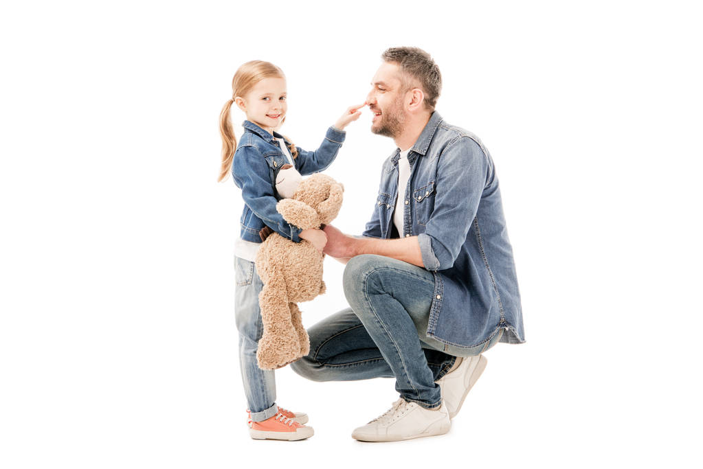 sonriente papá en jeans e hija con osito de peluche aislado en blanco
 - Foto, imagen