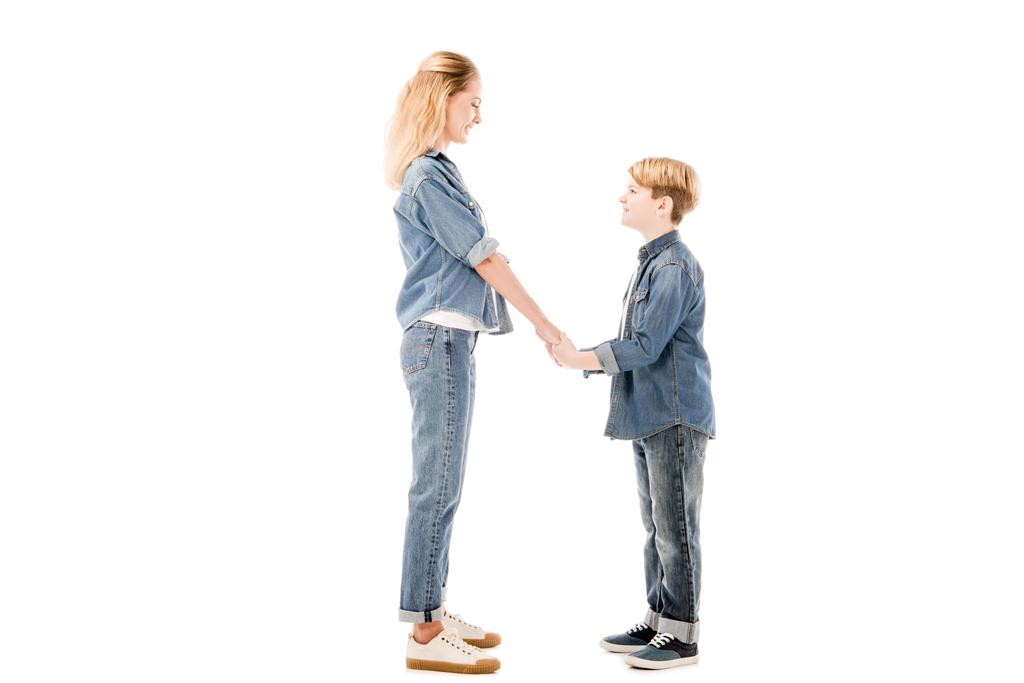 side view of happy mother and son holding hands and looking at each other isolated on white - Photo, Image