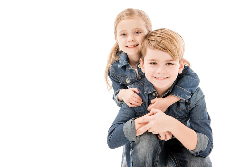 Ευτυχισμένα παιδιά που αγκαλιάζονται και κοιτάζουν την κάμερα απομονωμένη σε λευκό - Φωτογραφία, εικόνα