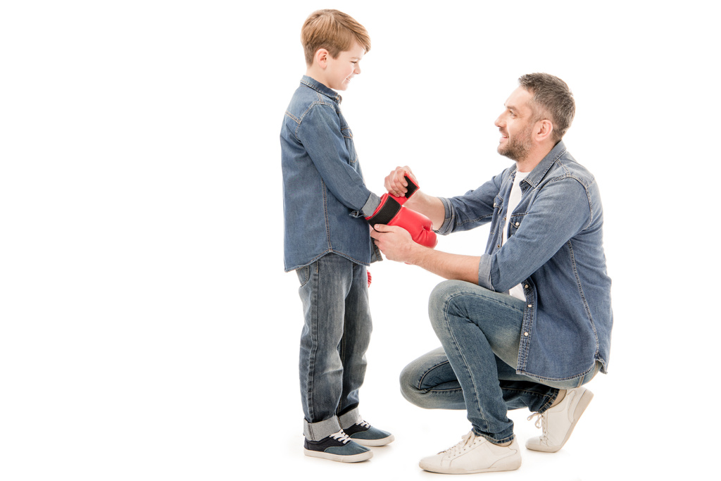 Papa helpt zoon om bokshandschoenen te dragen, geïsoleerd op wit - Foto, afbeelding