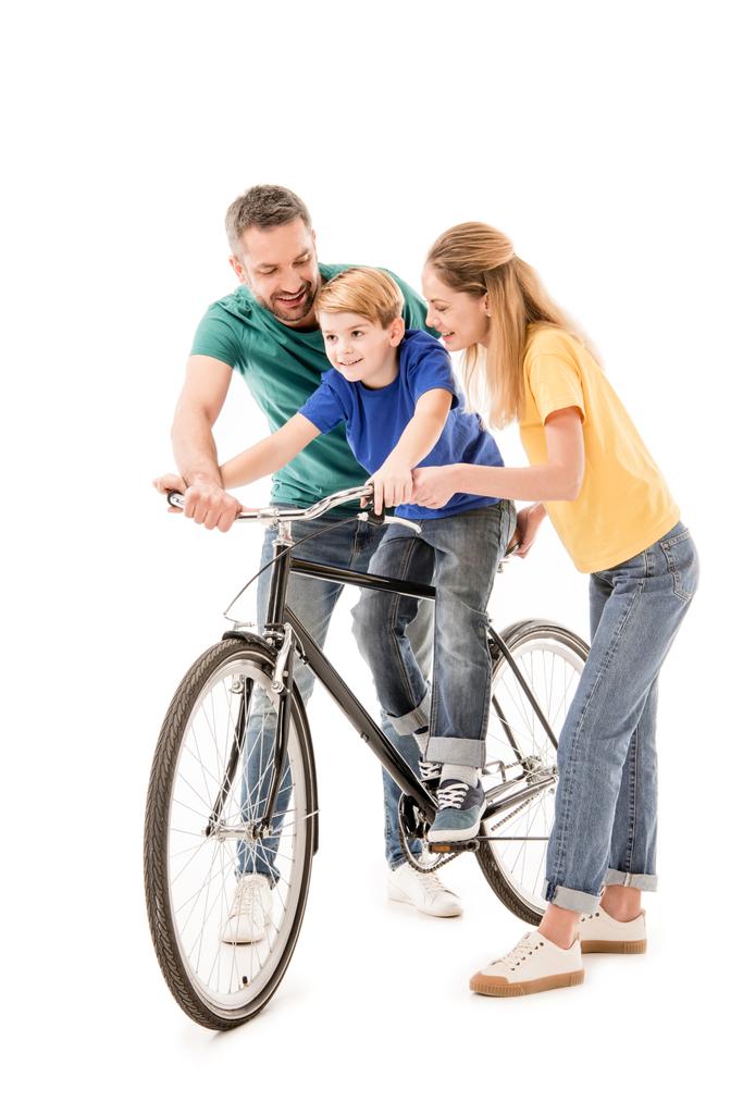 В полный рост улыбающиеся родители учат сына ездить на велосипеде, изолированном на белом
 - Фото, изображение