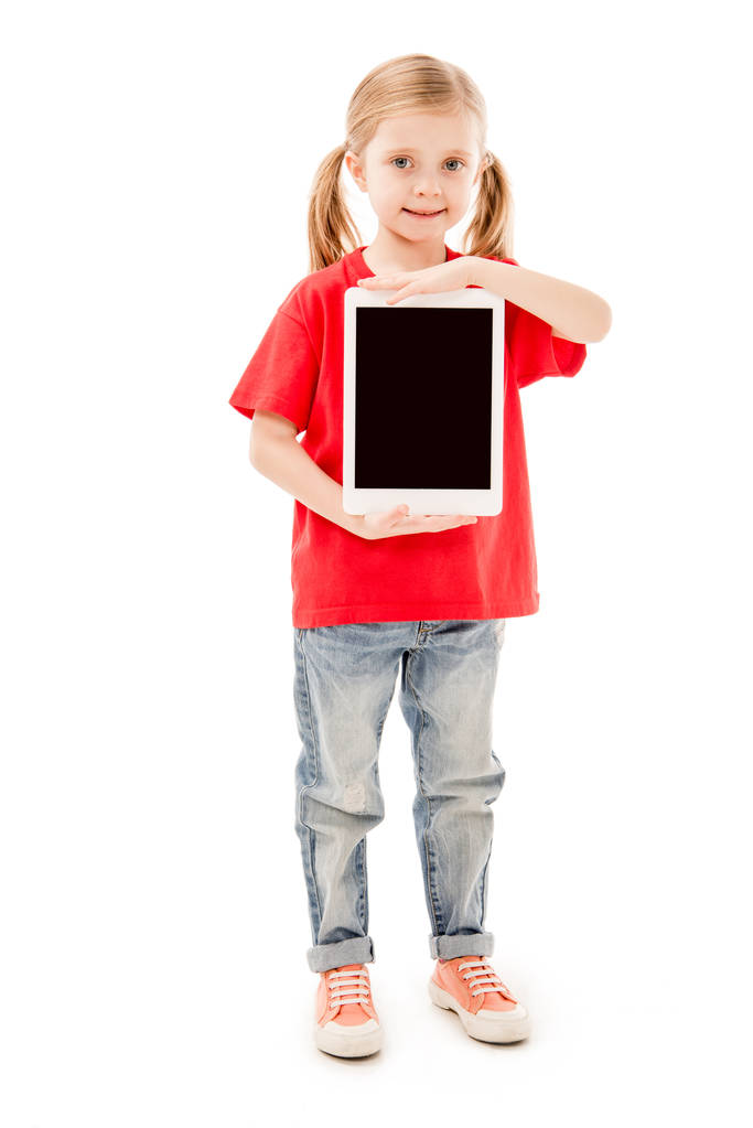 visão de comprimento total da criança sorridente em camiseta vermelha segurando tablet digital com tela em branco isolada em branco
 - Foto, Imagem