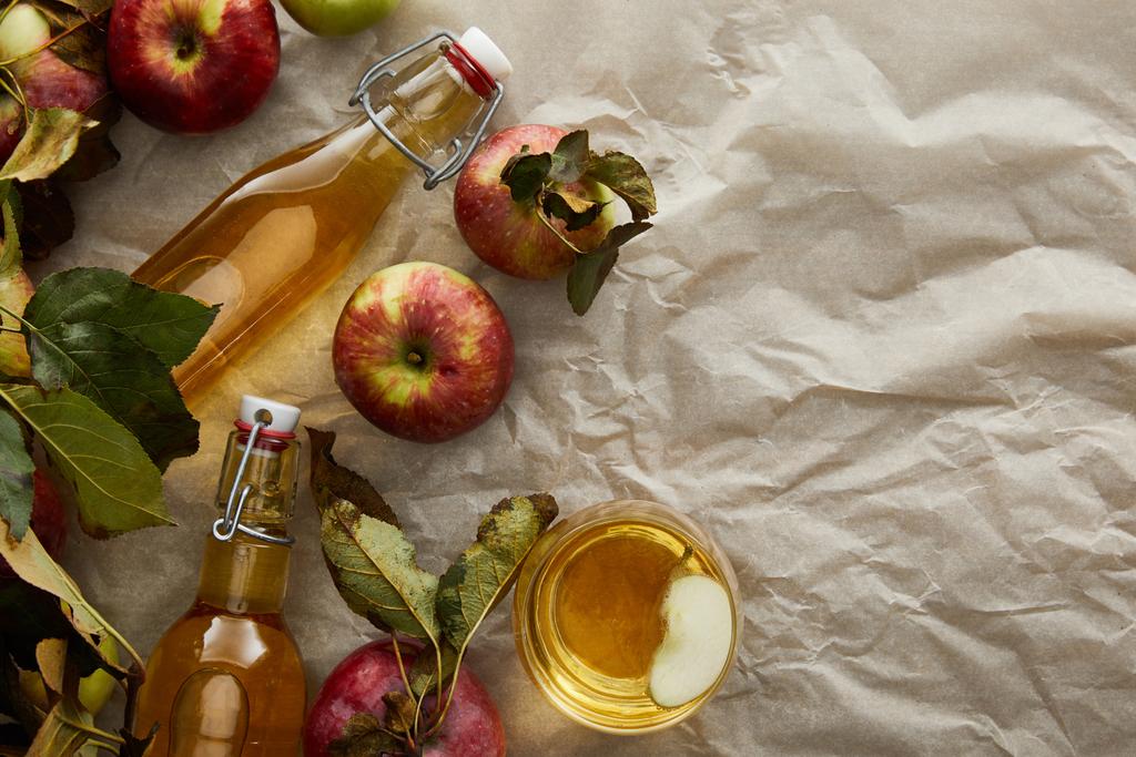 pohled na lahve a sklo s jablečným mošt nedaleko roztroušených jablek s prostorem pro kopírování - Fotografie, Obrázek