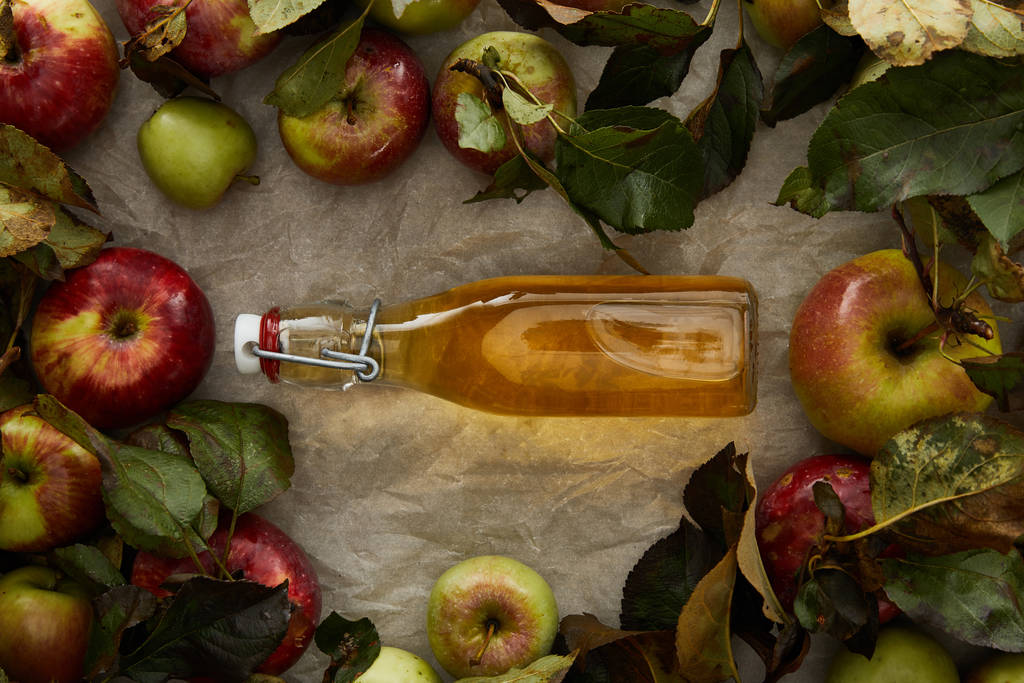 top view of bottle with cider between apples on parchment paper with copy space - Photo, Image