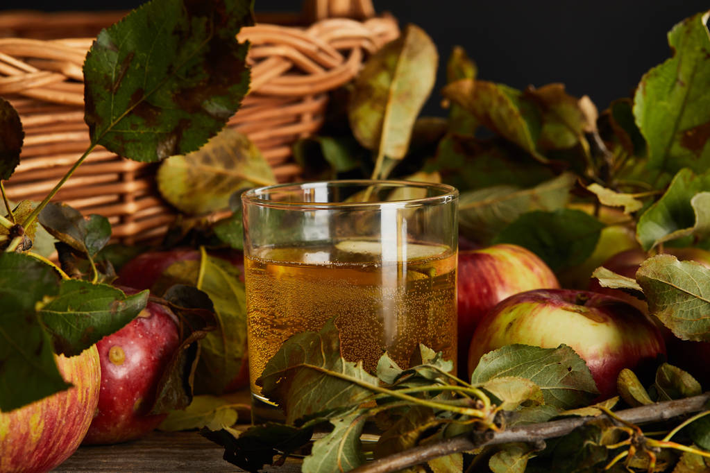 ποτήρι μηλίτη κοντά σε ψάθινο καλάθι και μήλα  - Φωτογραφία, εικόνα