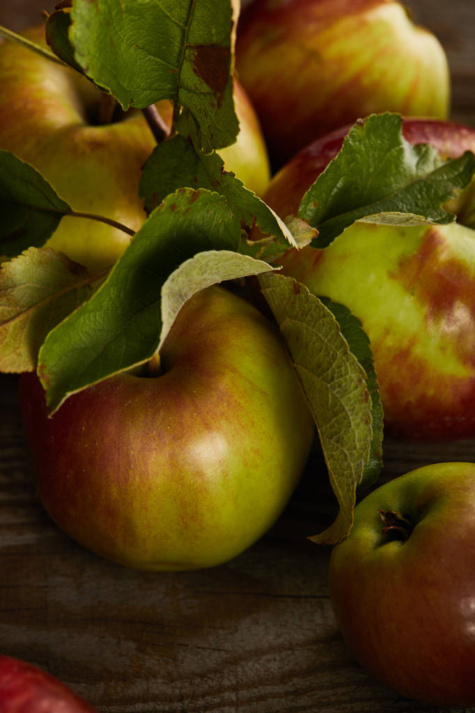 Nahaufnahme von saftigen frischen Äpfeln mit Blättern auf Holzoberfläche - Foto, Bild