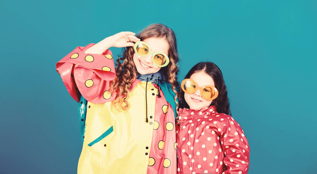 Kis lányok esőkabát és szemüveg. boldog kis lányok színes eső kabátot. esővédelem. Szivárvány. őszi divat. vidám gyerekek, Sisterhood. szórakoztunk. A legjobb módja annak, hogy kiad vakáció - Fotó, kép
